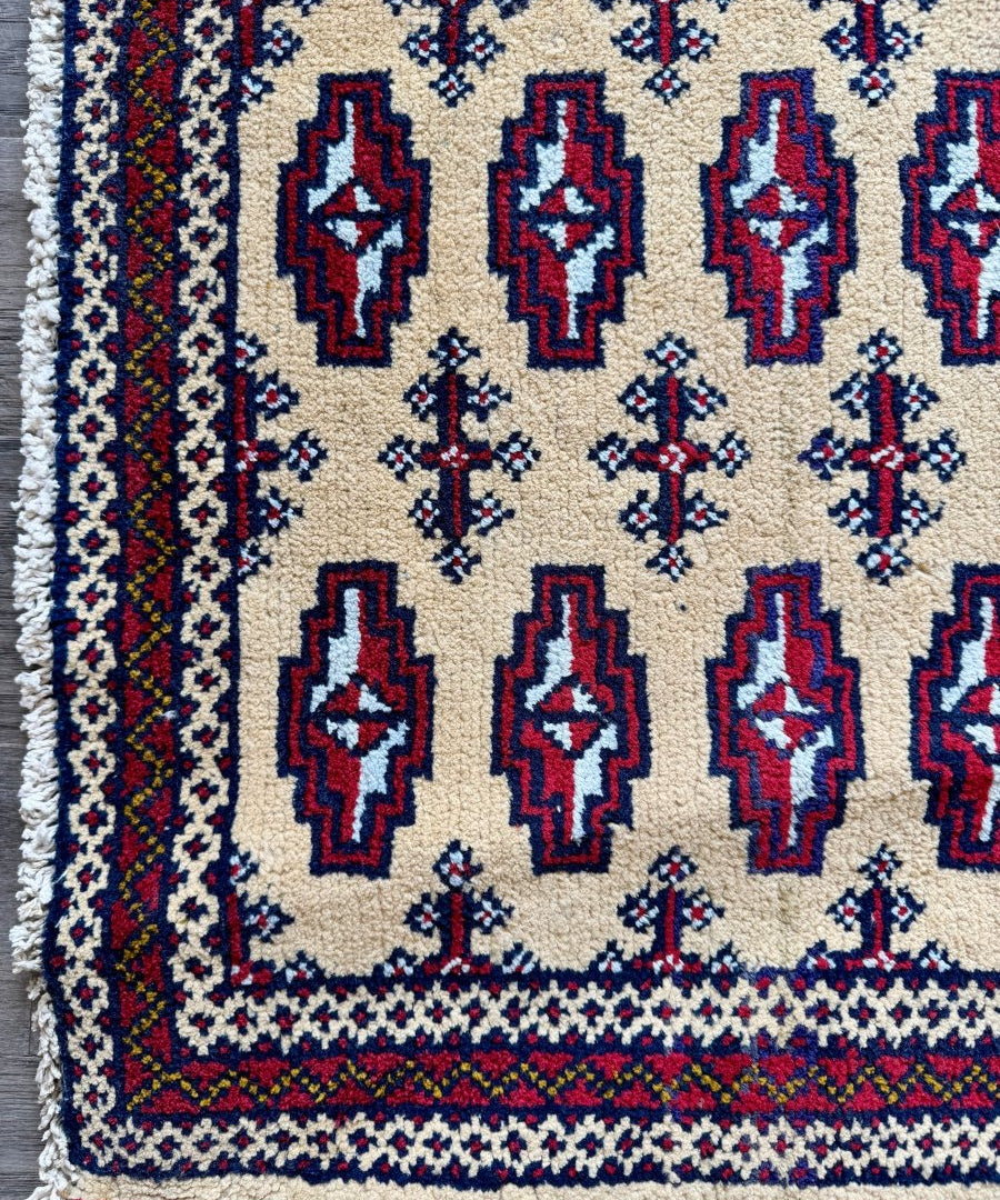 Turkmen mini rug with cream field, navy and red diamond motifs, blue floral accents