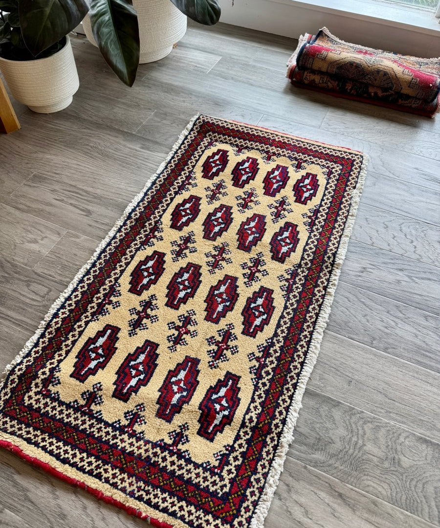 Mini rug on gray floor with cream background, dark red and blue medallion border