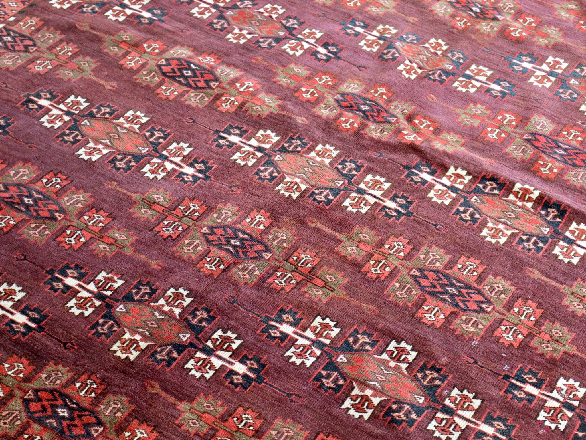Turkmen Yomut rug with burgundy field and repeating geometric pattern in navy, red, and white