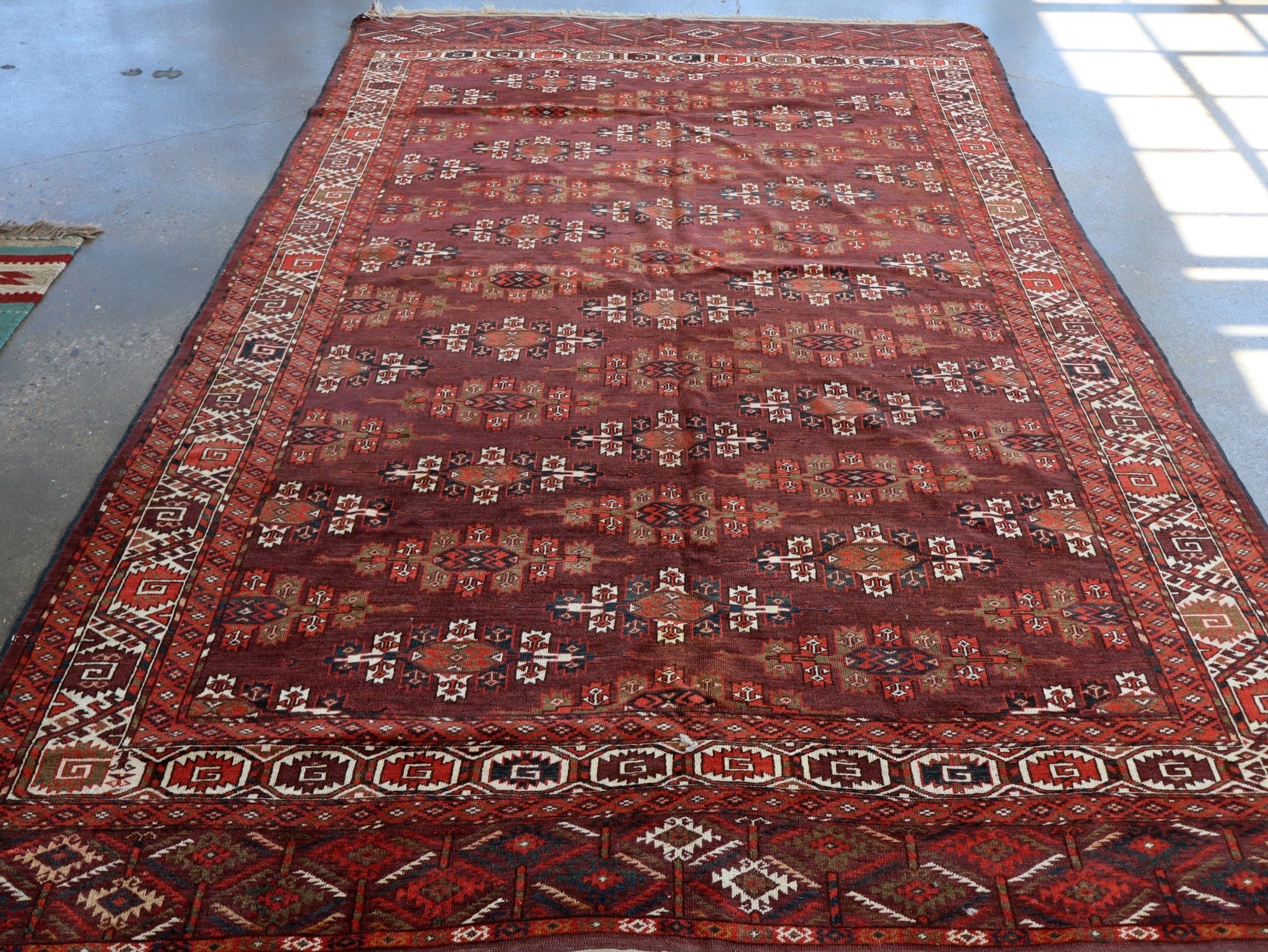 Turkmen Yomut rug centered full view with dark red field, geometric border, and short fringe