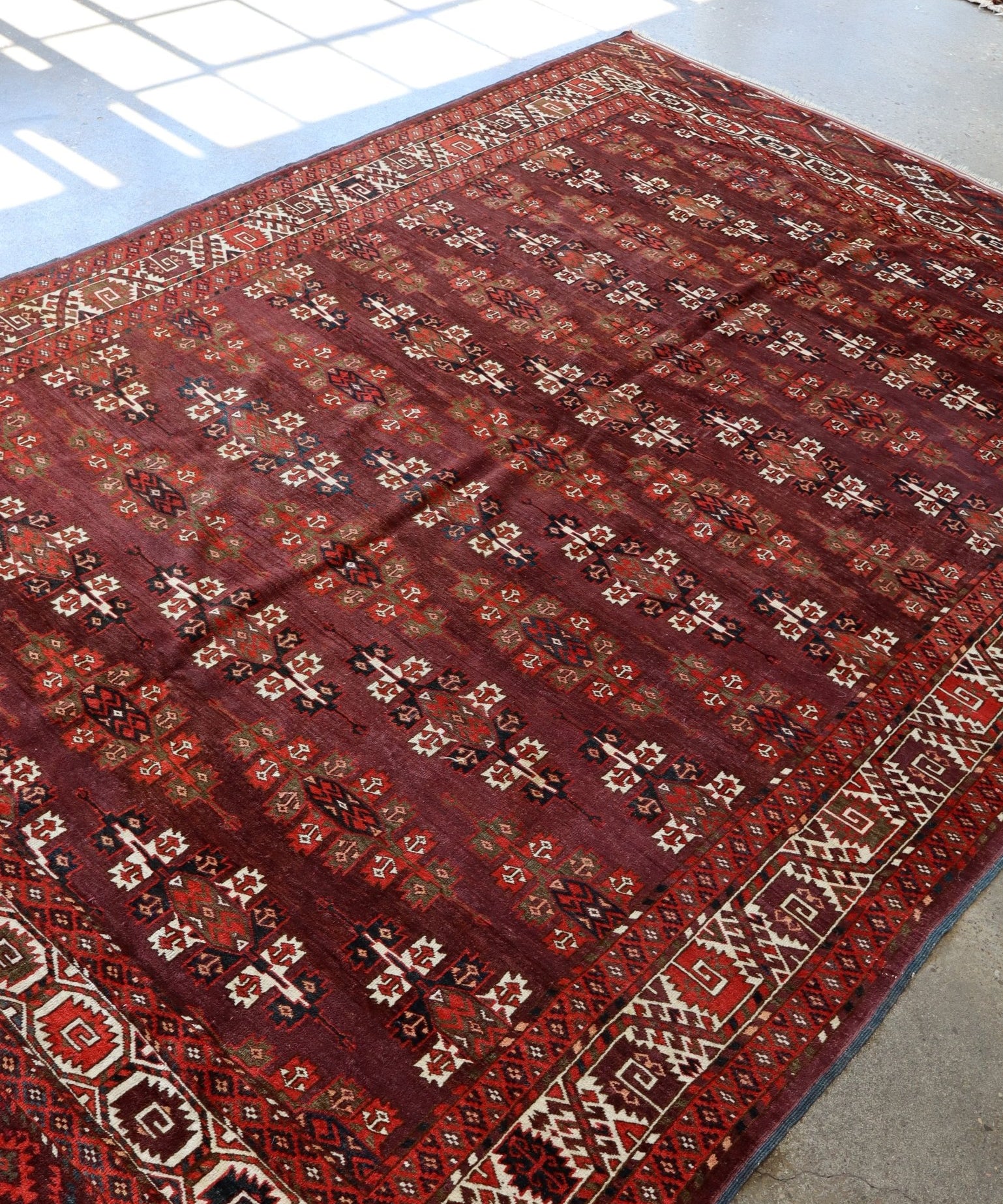 Turkmen Yomut rug full view with dark red field, ivory corner motifs, and patterned border
