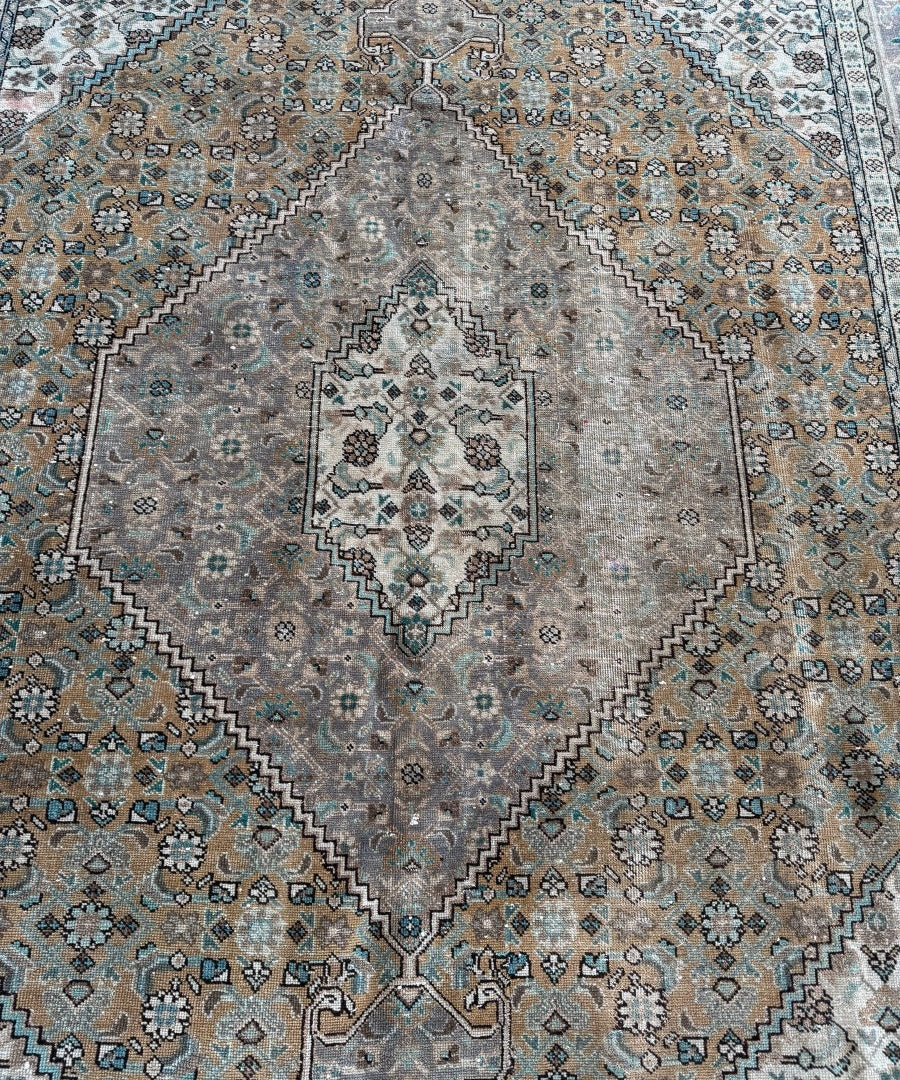 Close-up of Ardabil-style vintage rug pattern in gray, tan, and turquoise with diamond motifs
