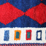 Persian Gabbeh rug edge with red diamond shapes on navy and cream trim