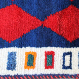 Persian Gabbeh rug edge with red diamond shapes on navy and cream trim