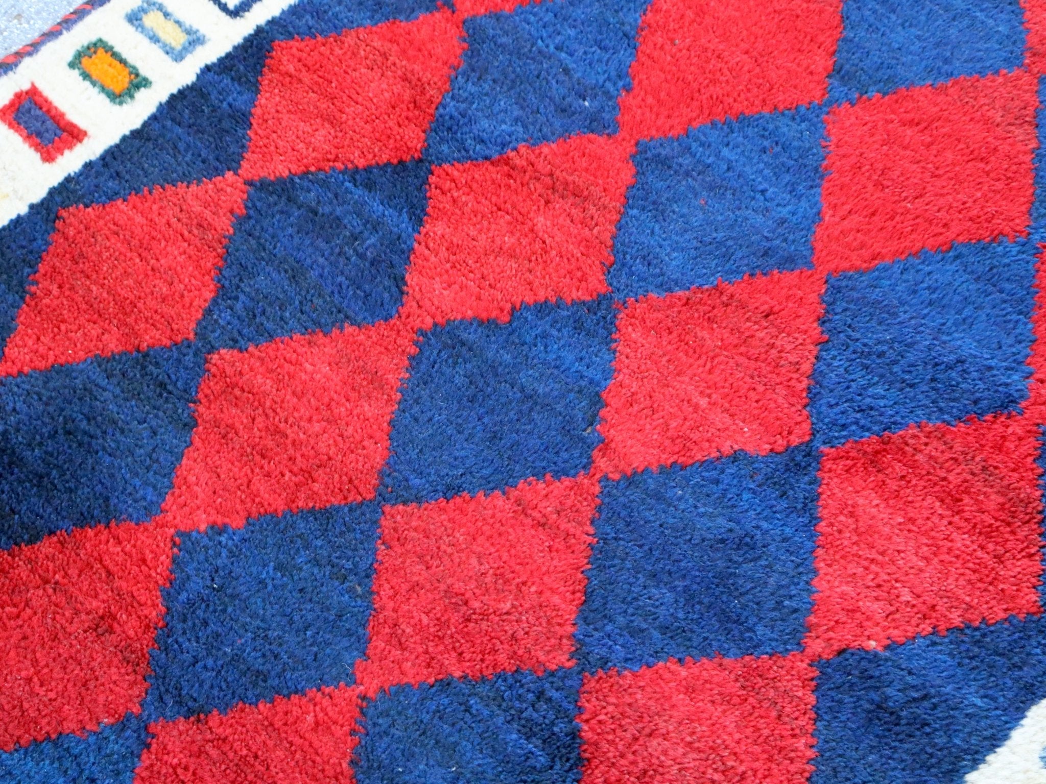Red and blue diamond-check Gabbeh rug with white border detail