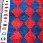 Side border close-up with blue and cream geometric pattern beside red navy diamonds