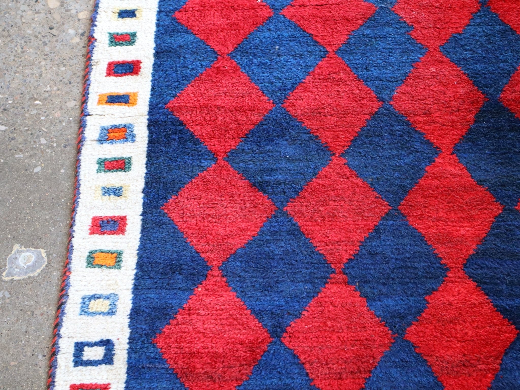 Side border close-up with blue and cream geometric pattern beside red navy diamonds