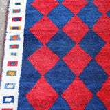 Side border close-up with blue and cream geometric pattern beside red navy diamonds