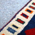 Cream border with multicolor geometric motifs on a navy ground; red accents
