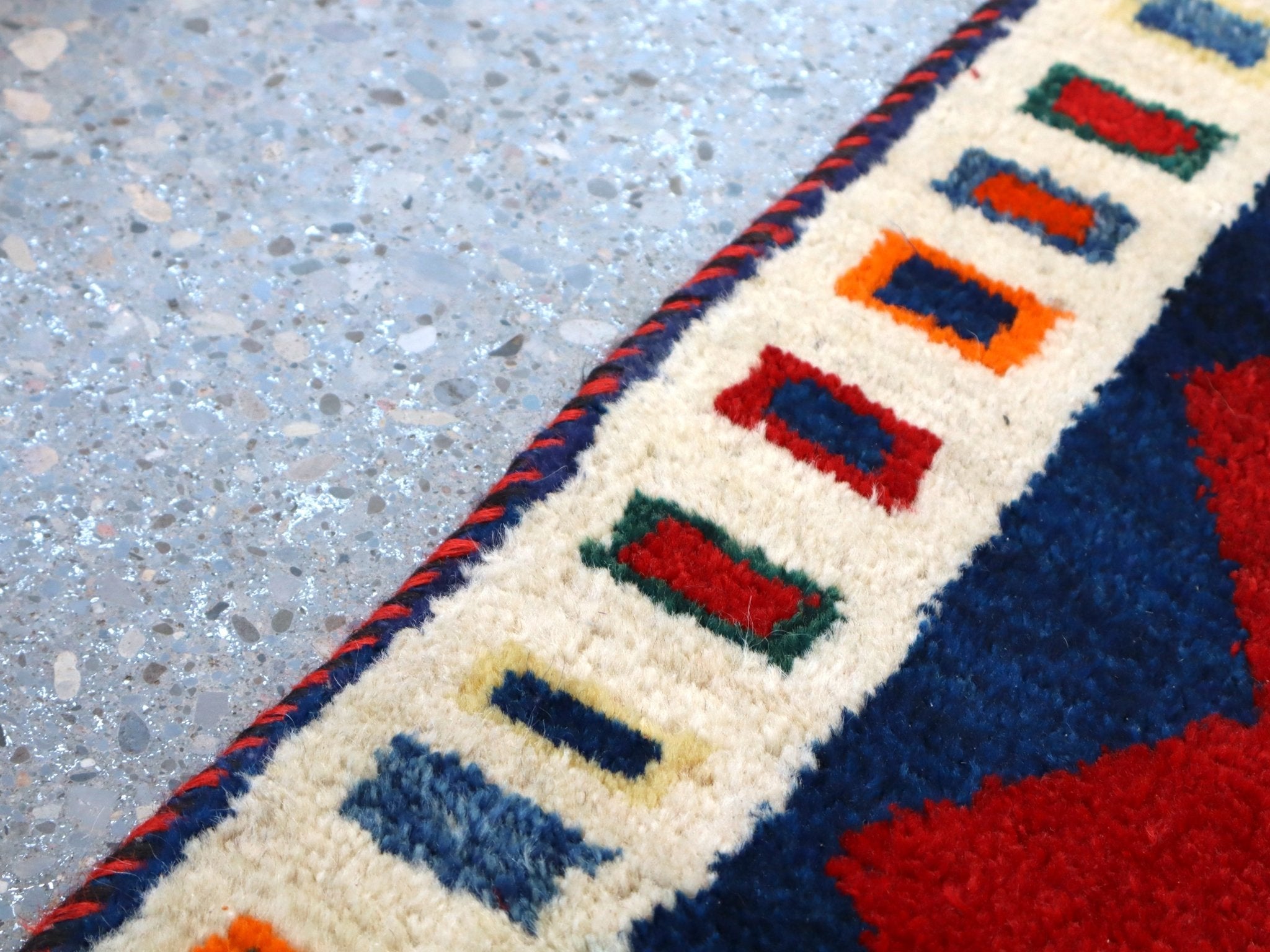 Cream border with multicolor geometric motifs on a navy ground; red accents
