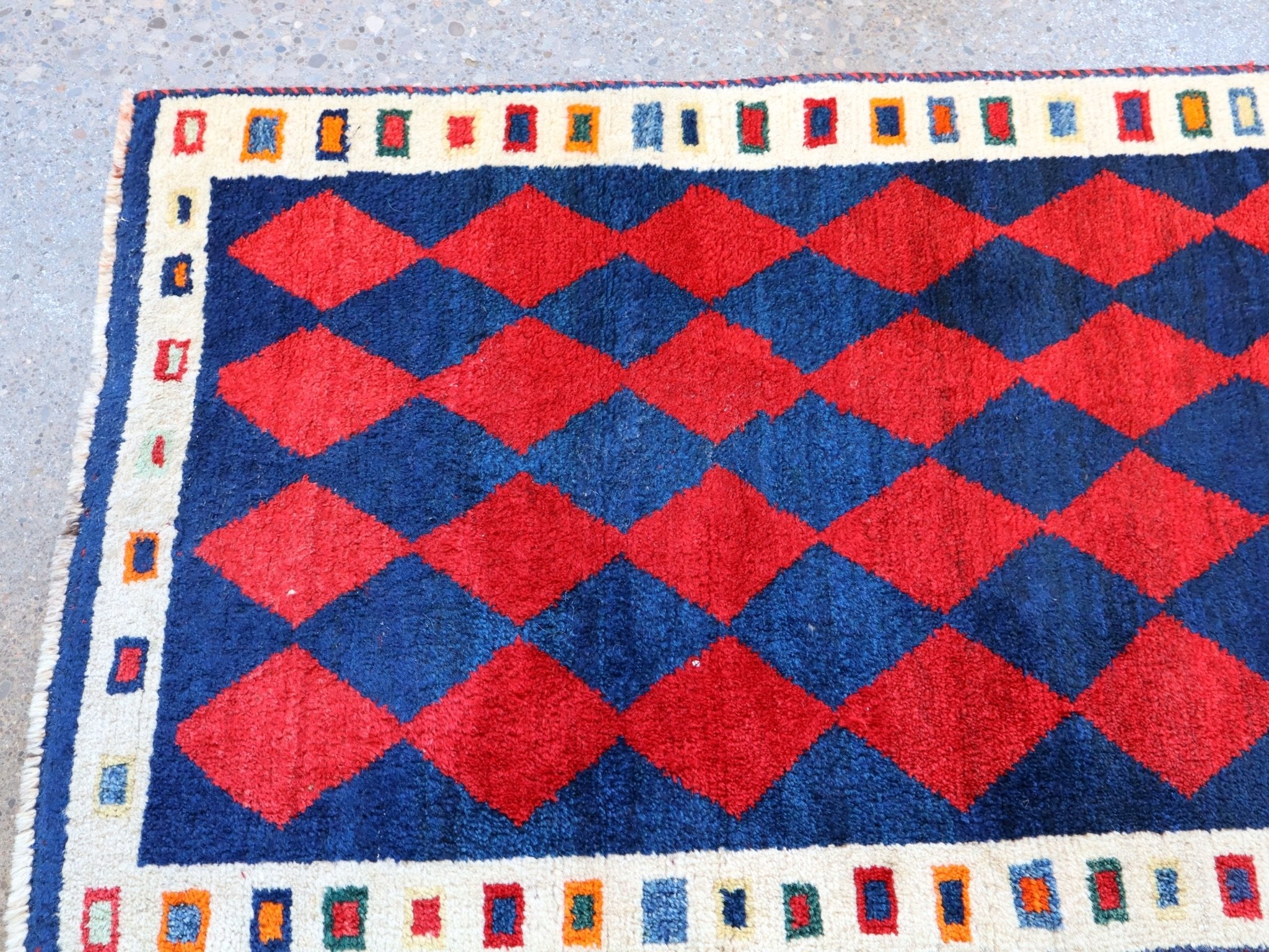 Red diamond pattern Gabbeh rug with navy field and white side border