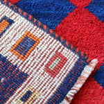 Close-up of cream border weave with multicolor blocks on navy and red diamond rug