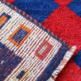 Close-up of cream border weave with multicolor blocks on navy and red diamond rug