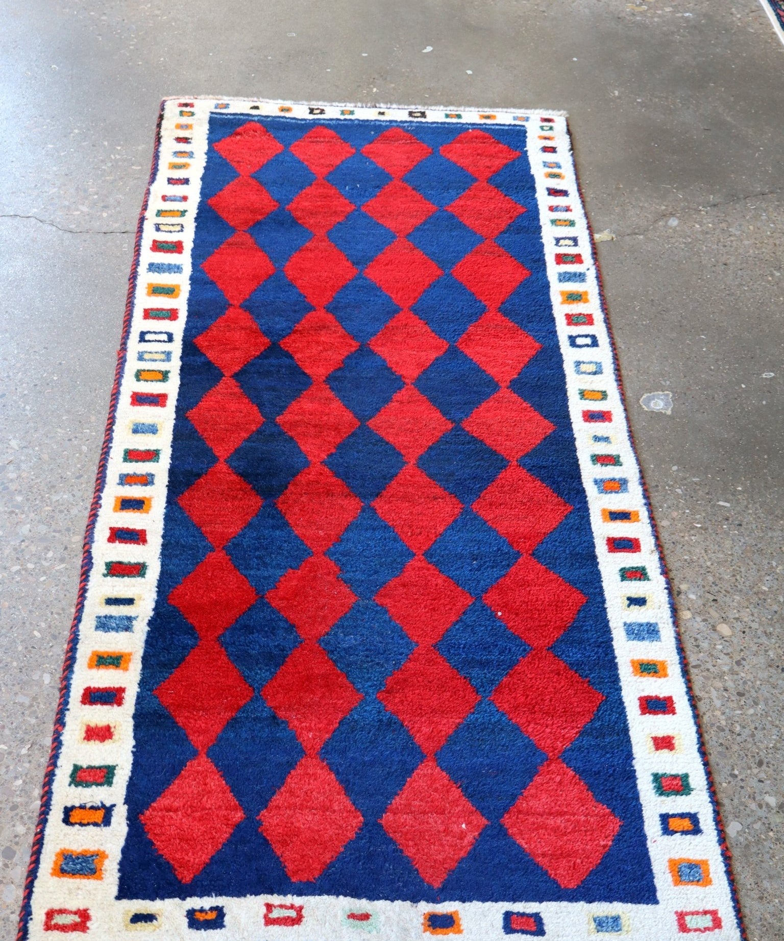 Rectangular Gabbeh rug with red and blue diamond grid and geometric border