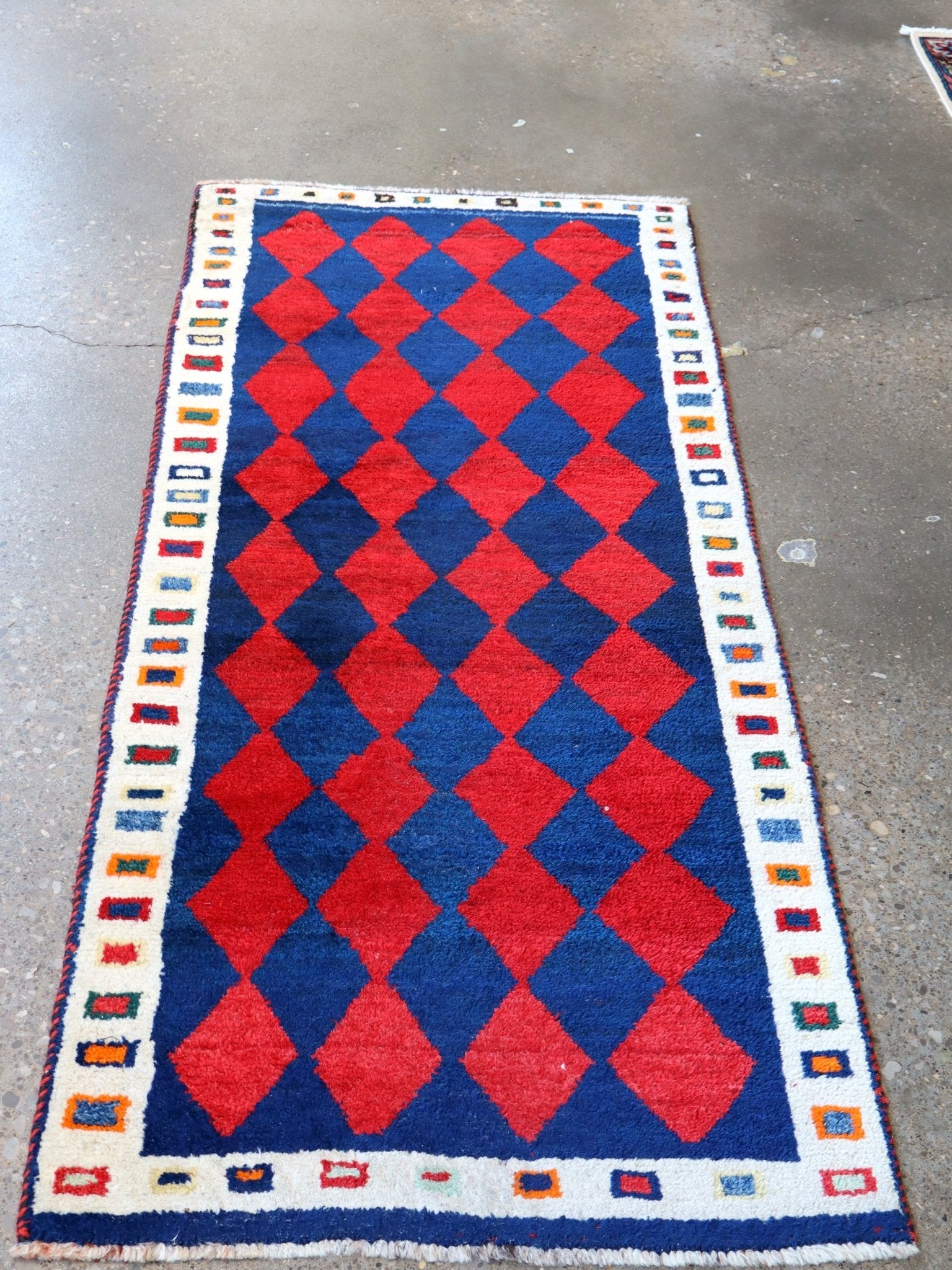 Rectangular Gabbeh rug with red and blue diamond grid and geometric border