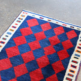 Vintage Persian Gabbeh rug corner with red and navy checker diamonds and cream trim