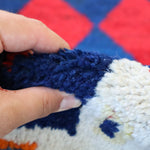 Navy and cream pile on a Persian Gabbeh rug with red diamond accents; hand touch