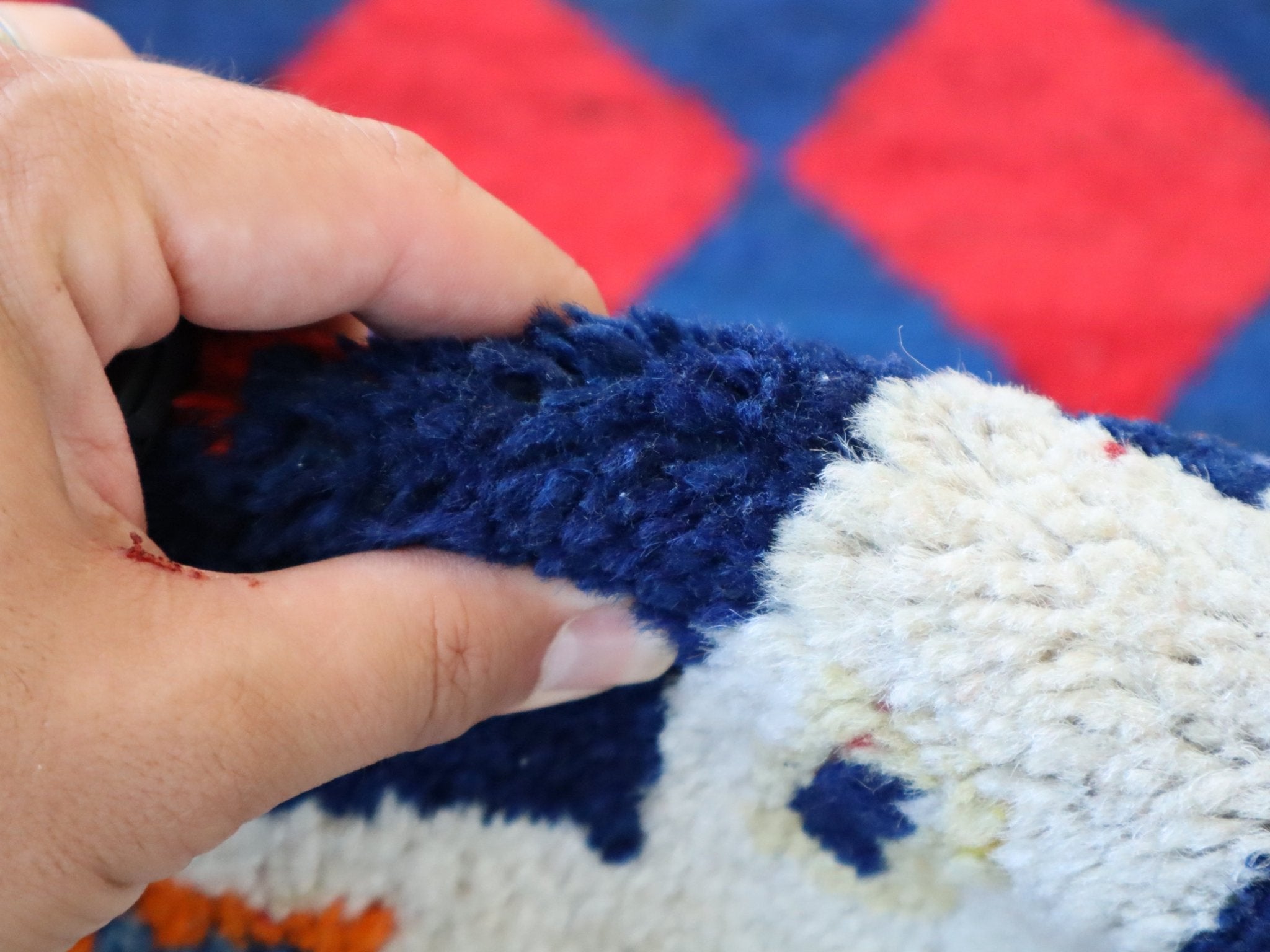 Navy and cream pile on a Persian Gabbeh rug with red diamond accents; hand touch