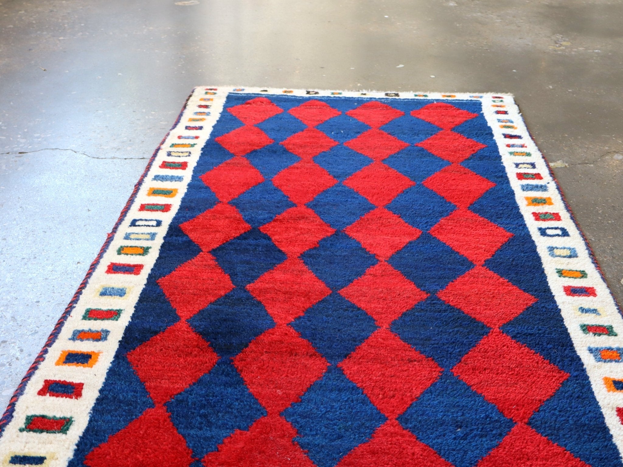 Vintage Persian Gabbeh rug in red and navy with cream border and diamond grid