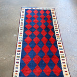 Vintage Persian Gabbeh rug with repeating red-and-navy diamonds and cream border