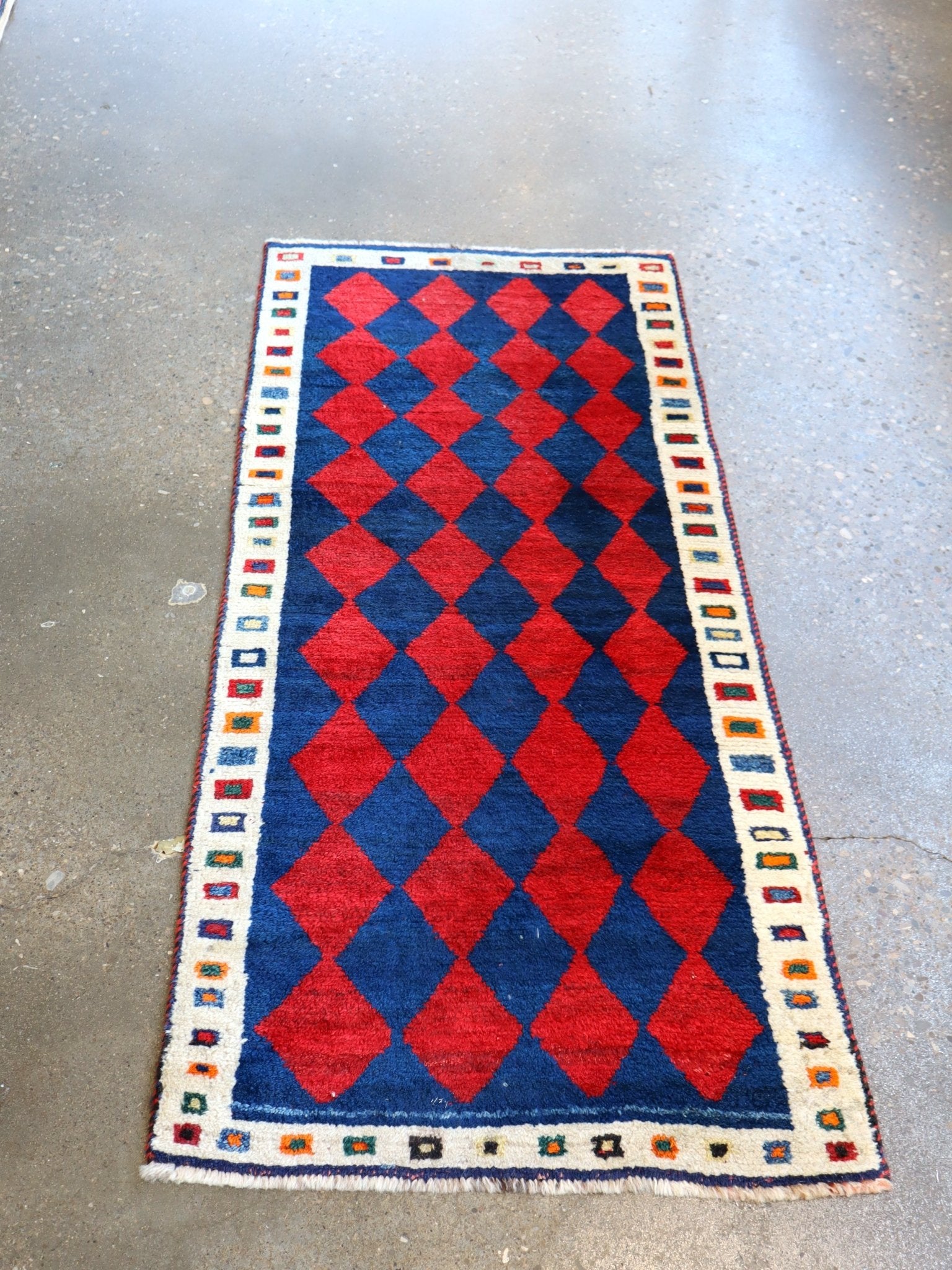 Vintage Persian Gabbeh rug with repeating red-and-navy diamonds and cream border