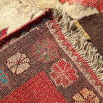 Corner edge of Persian Gabbeh rug with fringe and detailed border weave pattern.