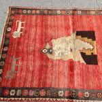 Gabbeh rug top view with red field, large cream animal medallion, and dark decorative border