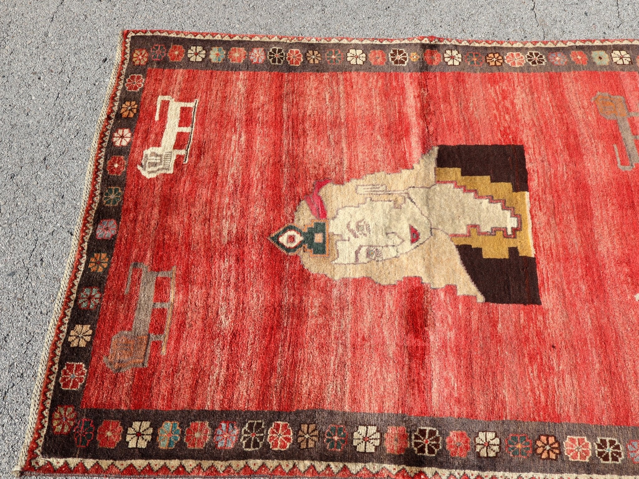 Gabbeh rug top view with red field, large cream animal medallion, and dark decorative border