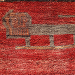 Persian Gabbeh rug detail showing cream and dark animal-like motif on red field.