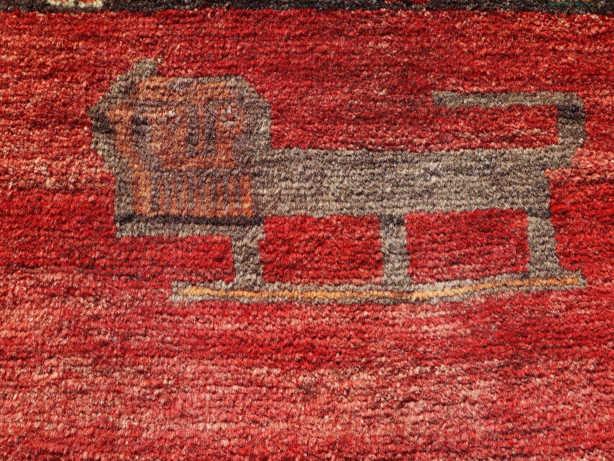 Persian Gabbeh rug detail showing cream and dark animal-like motif on red field.