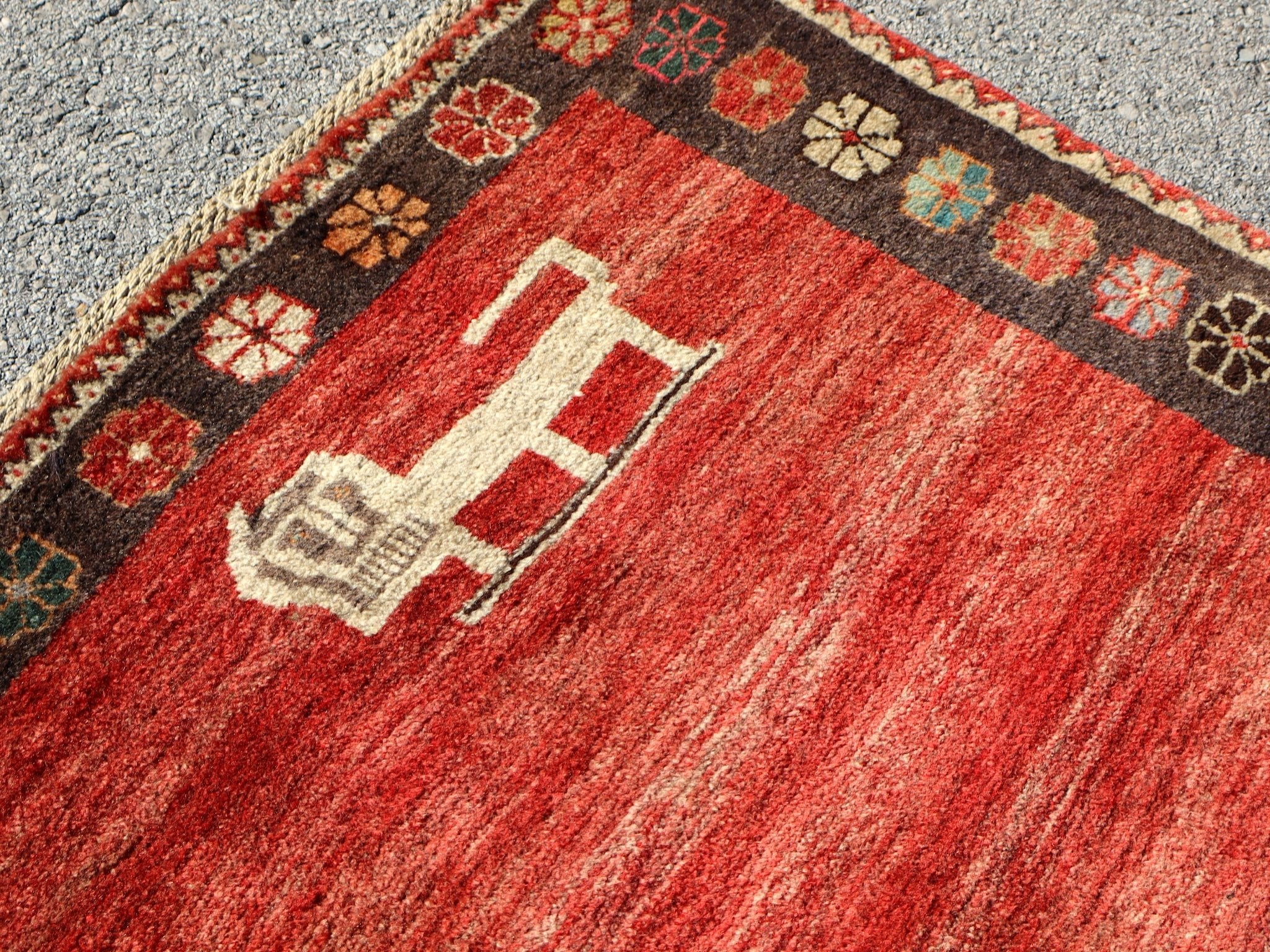 Close-up of red Persian Gabbeh rug with cream abstract medallion and dark border.