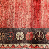 Gabbeh rug close-up with red field, cream highlights, and dark geometric border motifs