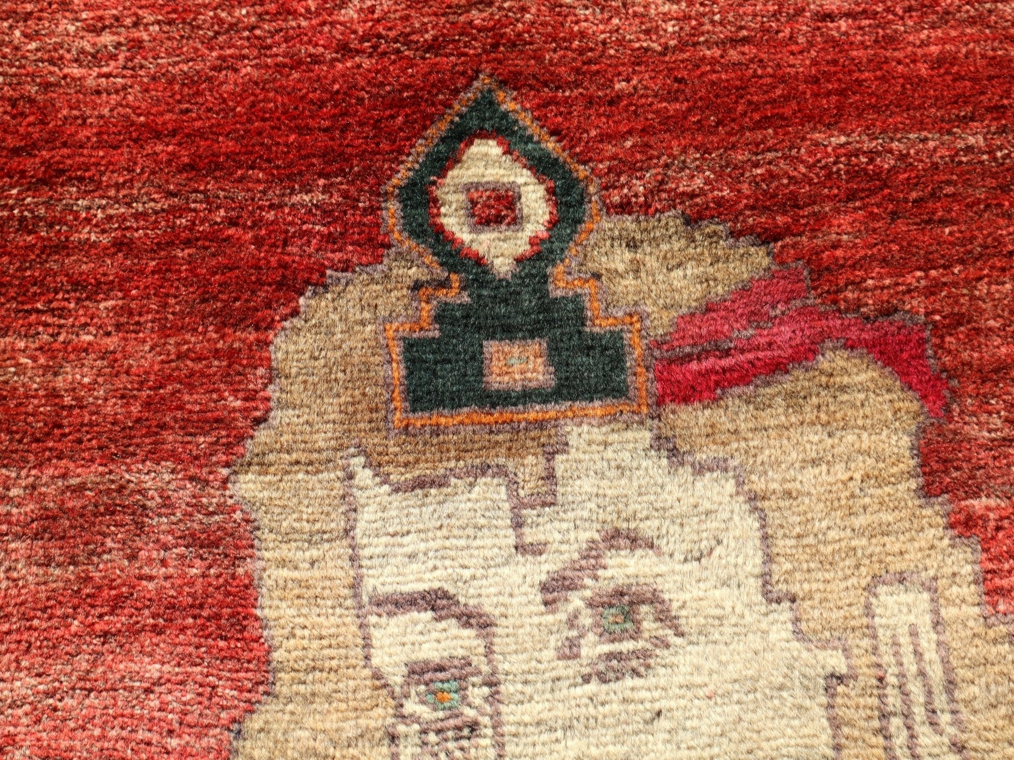 Close-up portrait motif on a red Persian Gabbeh rug with cream figure and dark accents.