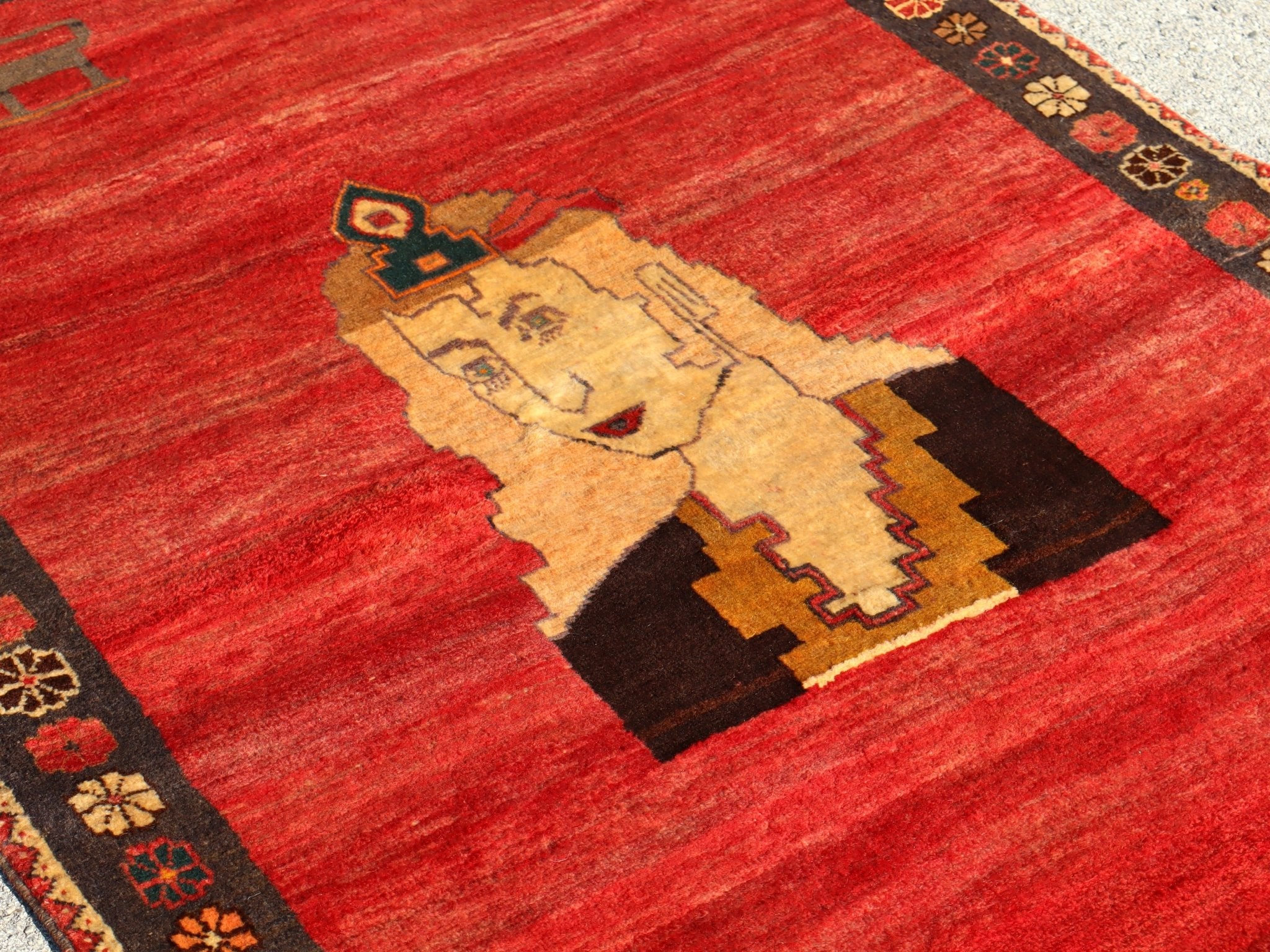 Persian Gabbeh rug close-up of cream portrait with red background and dark corner border.