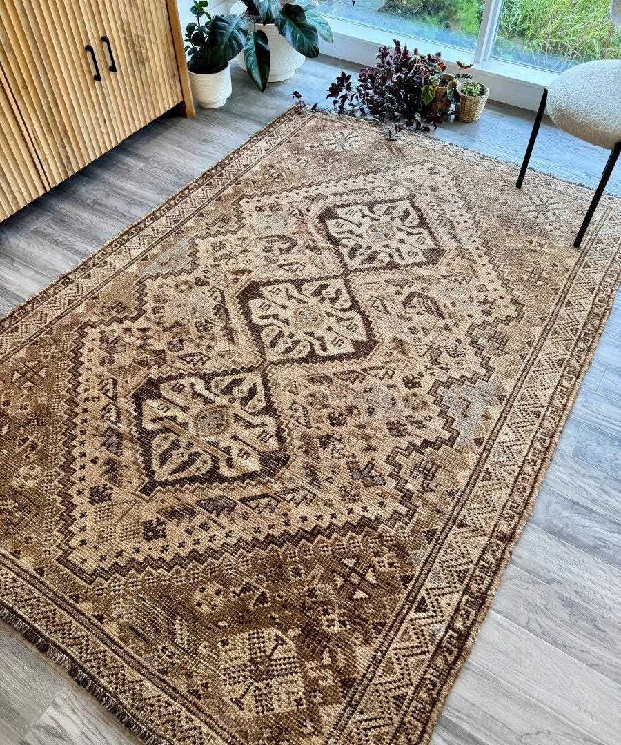 Vintage Shiraz rug with beige and dark brown allover geometric motif, on a light wood floor
