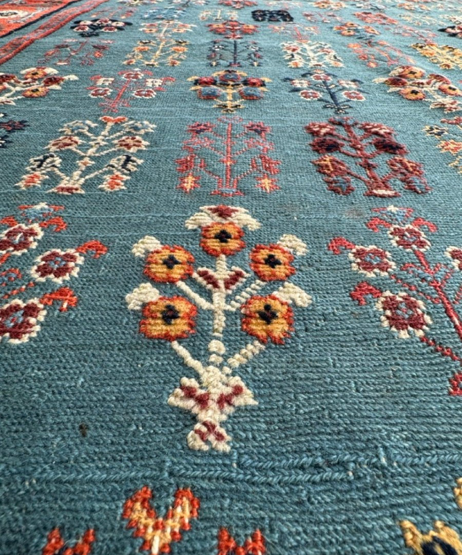 Close-up of blue Gabbeh-style kilim rug with colorful floral crosses and vine details
