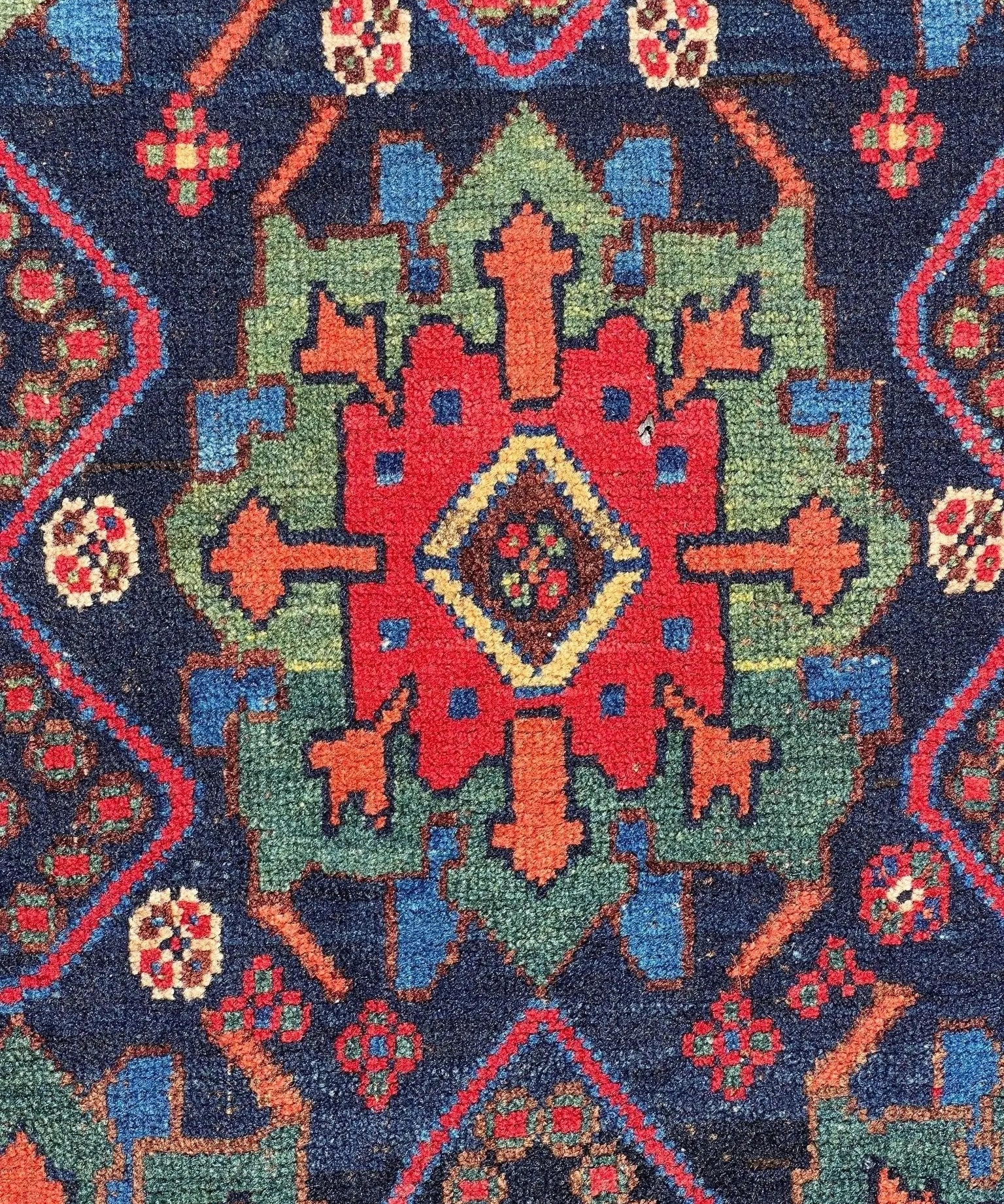 Antique Afshar rug close-up: dark blue with red, green and cream star medallions