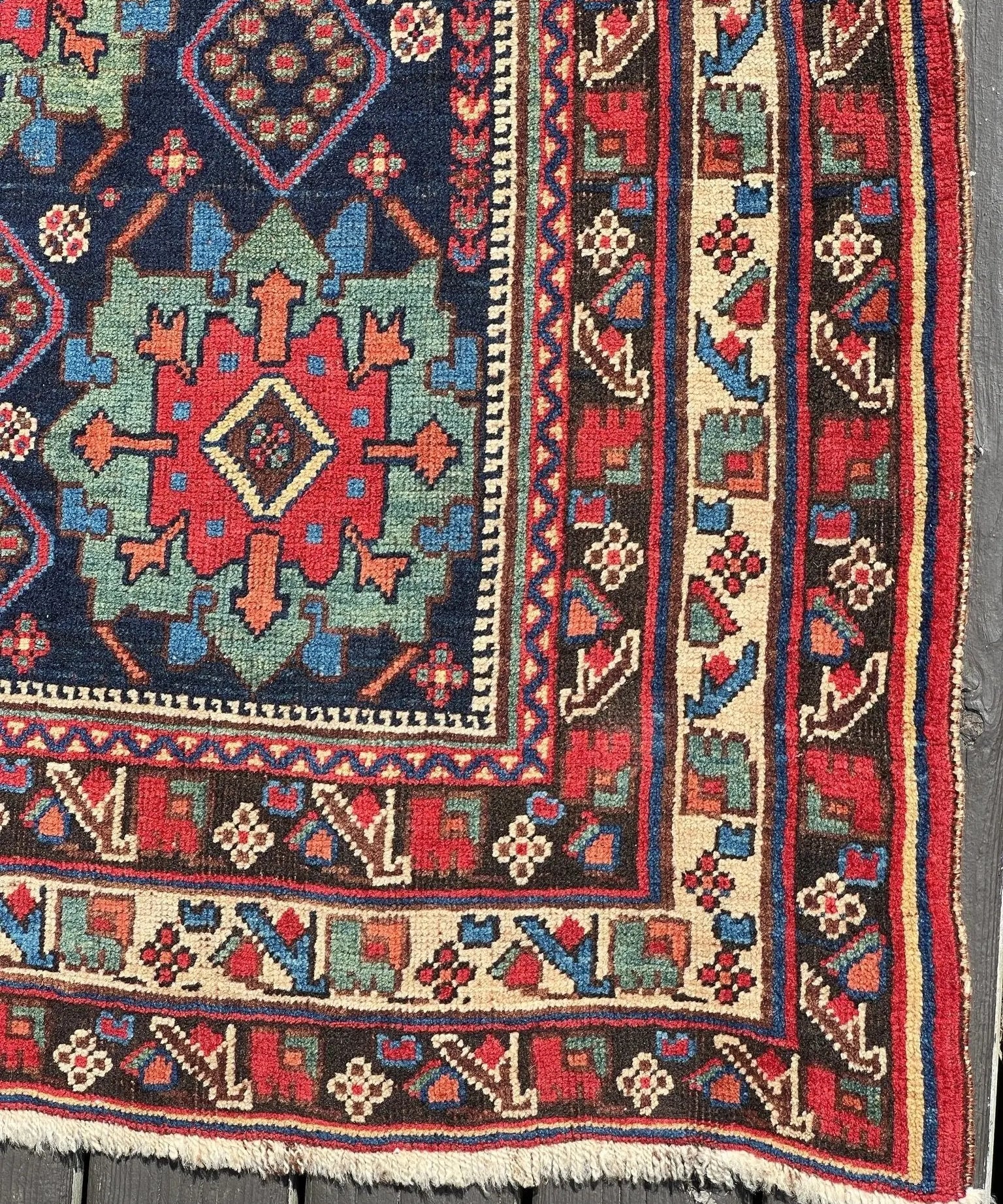 Antique Afshar rug border detail: dark blue with red trim and multicolor corner motifs