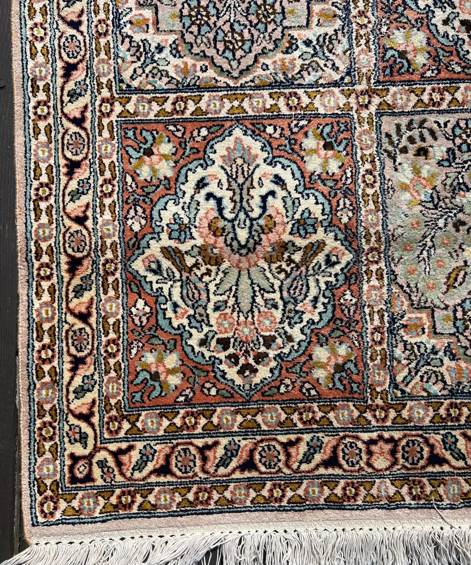 Indian Kashmir rug close-up of central floral medallion and borders, fringed bottom