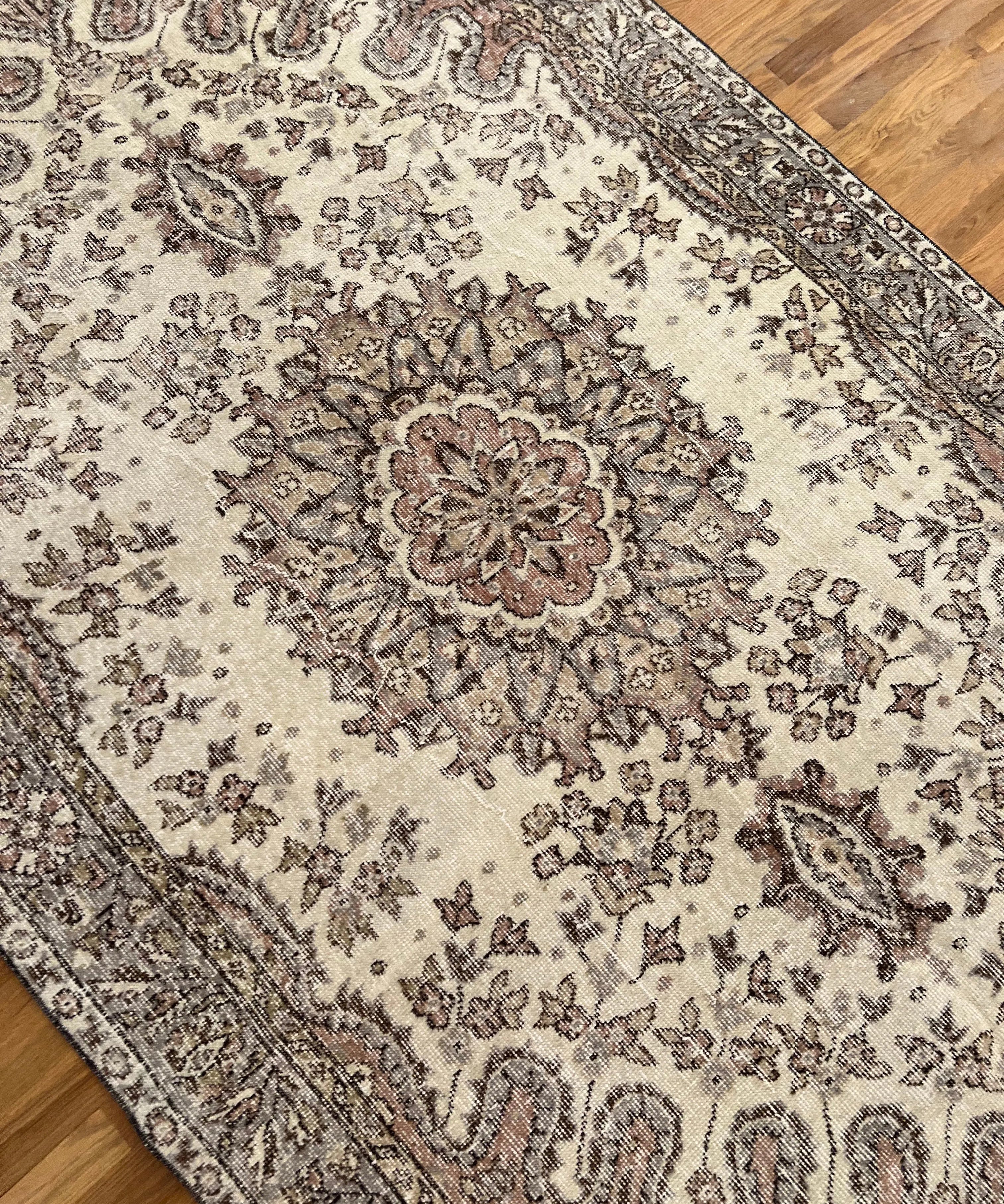 Vintage Turkish Oushak rug corner detail with cream, dark motifs, and thin striped border