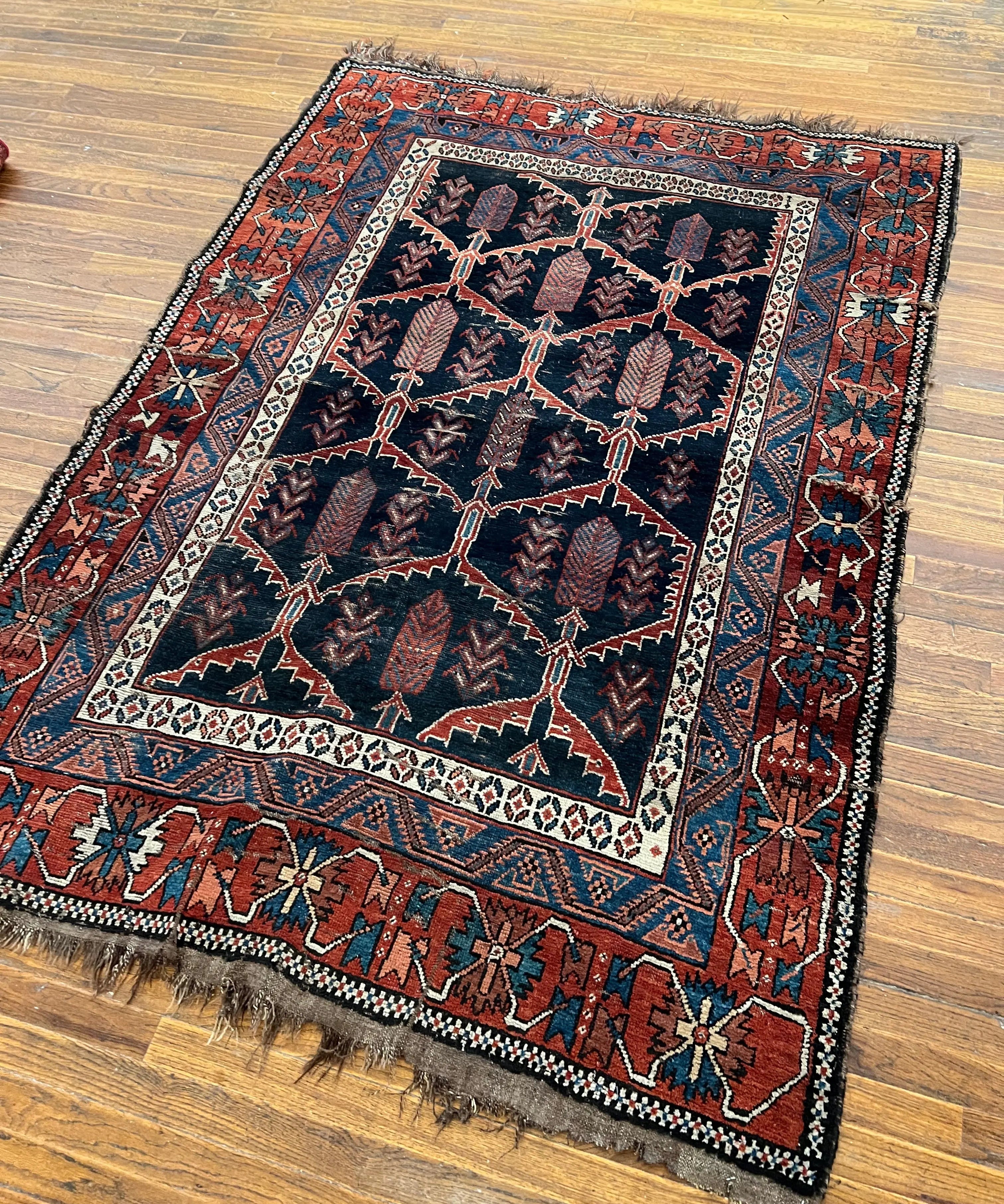 Antique Persian Afshar rug with navy field, rust and teal geometric medallion, fringed border