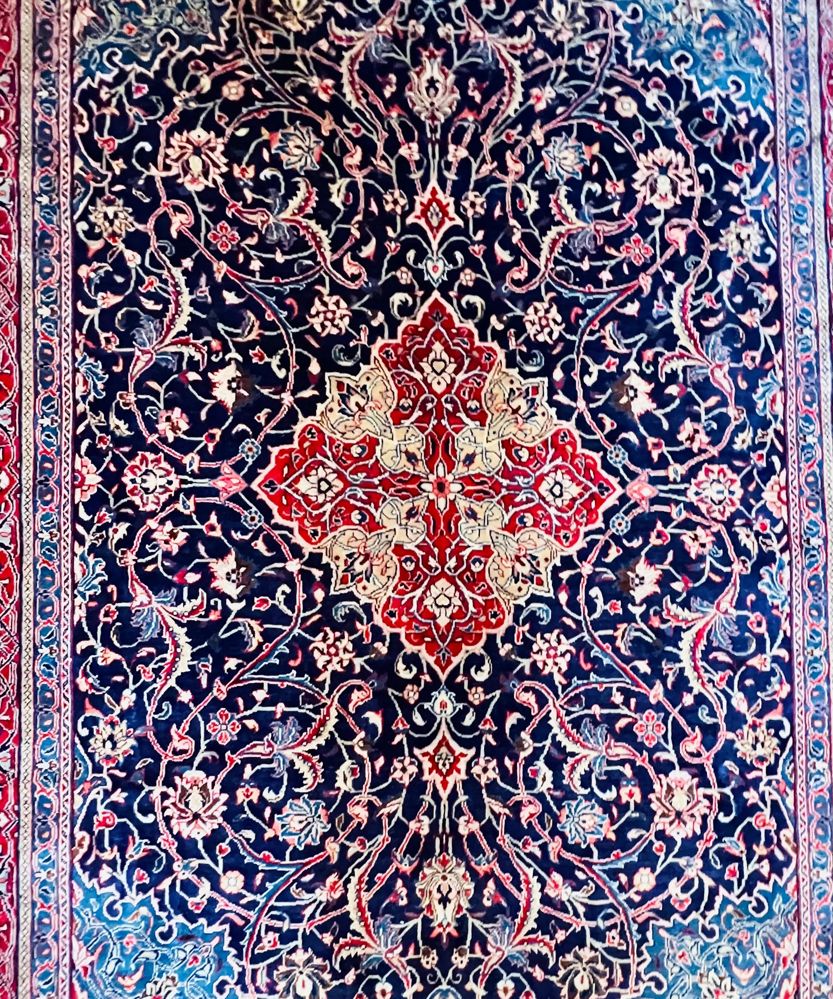 Persian arak rug with dark navy floral medallion pattern and red accents