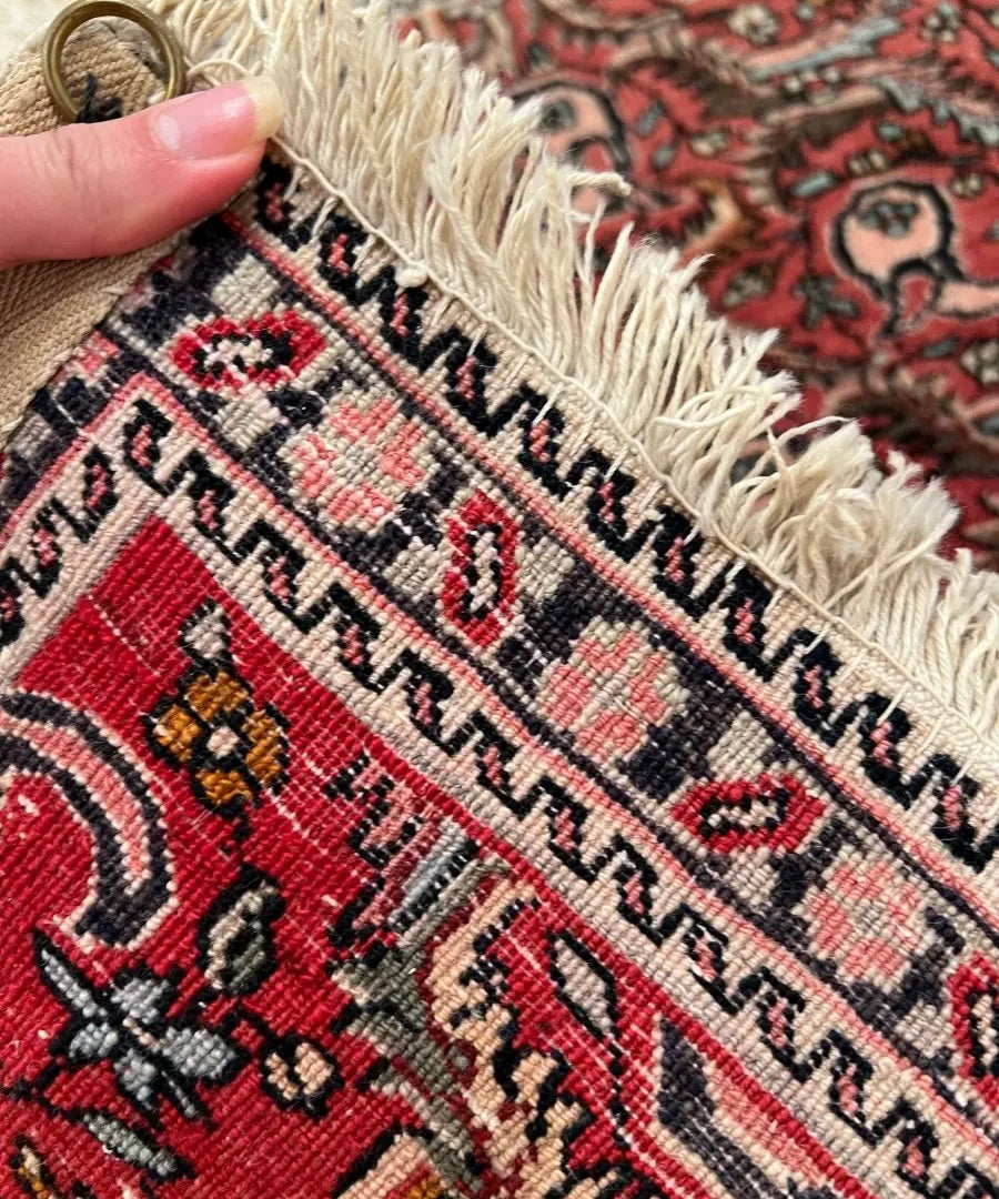 Rug corner detail with red, cream, and black geometric motifs and fringe