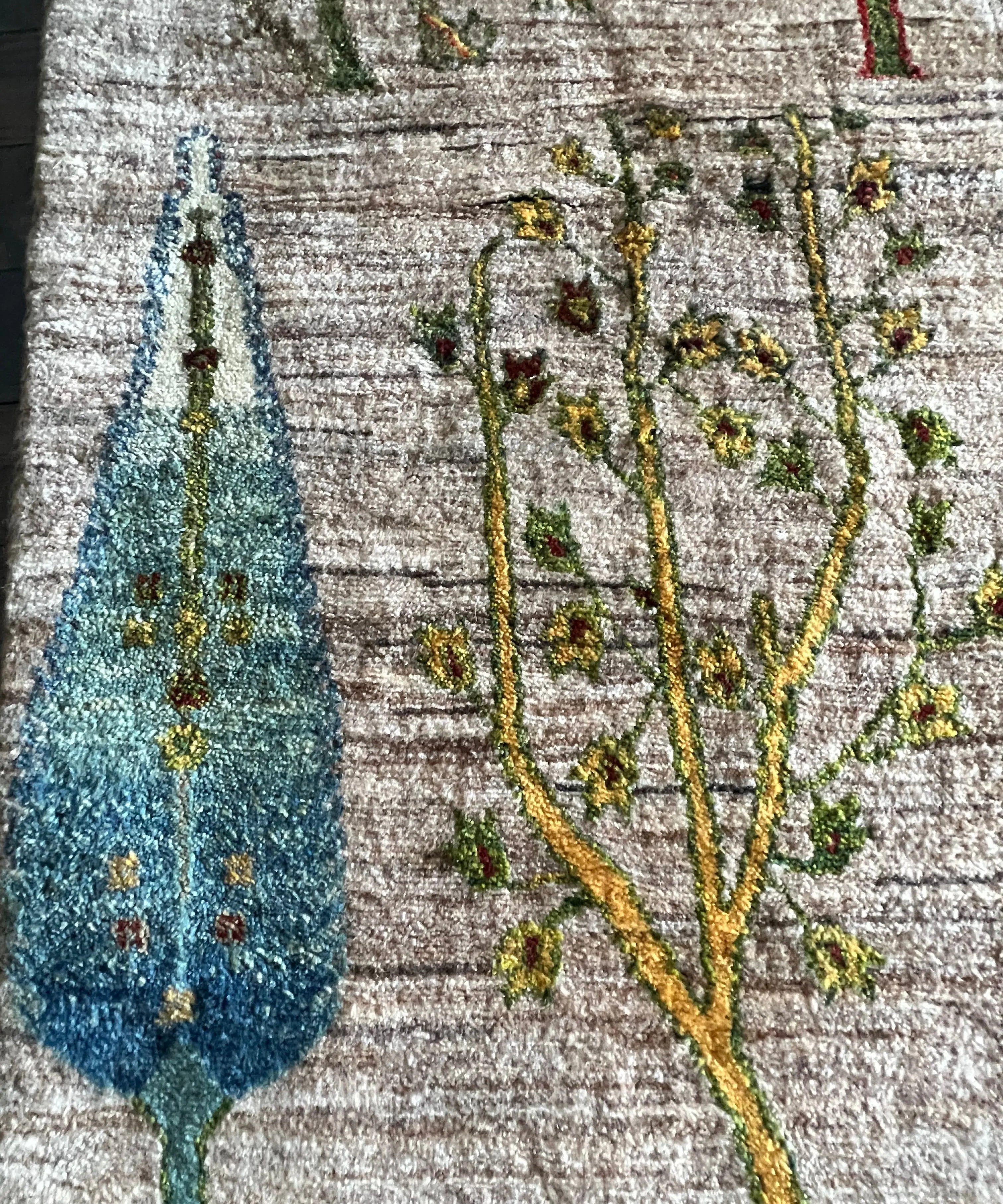 Textured rug close-up with teal tree and small floral details on light ground
