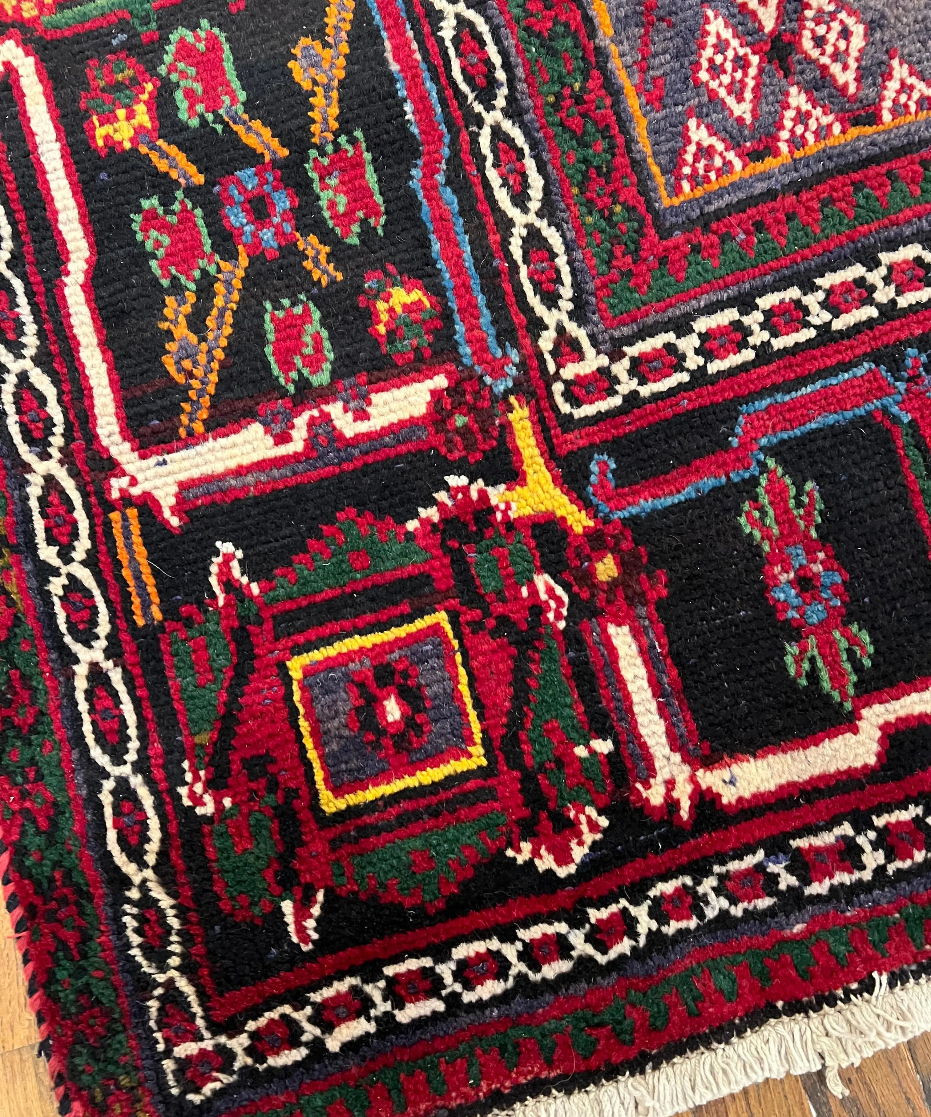 Rug corner detail with red center, black border, and multicolor decorative shapes