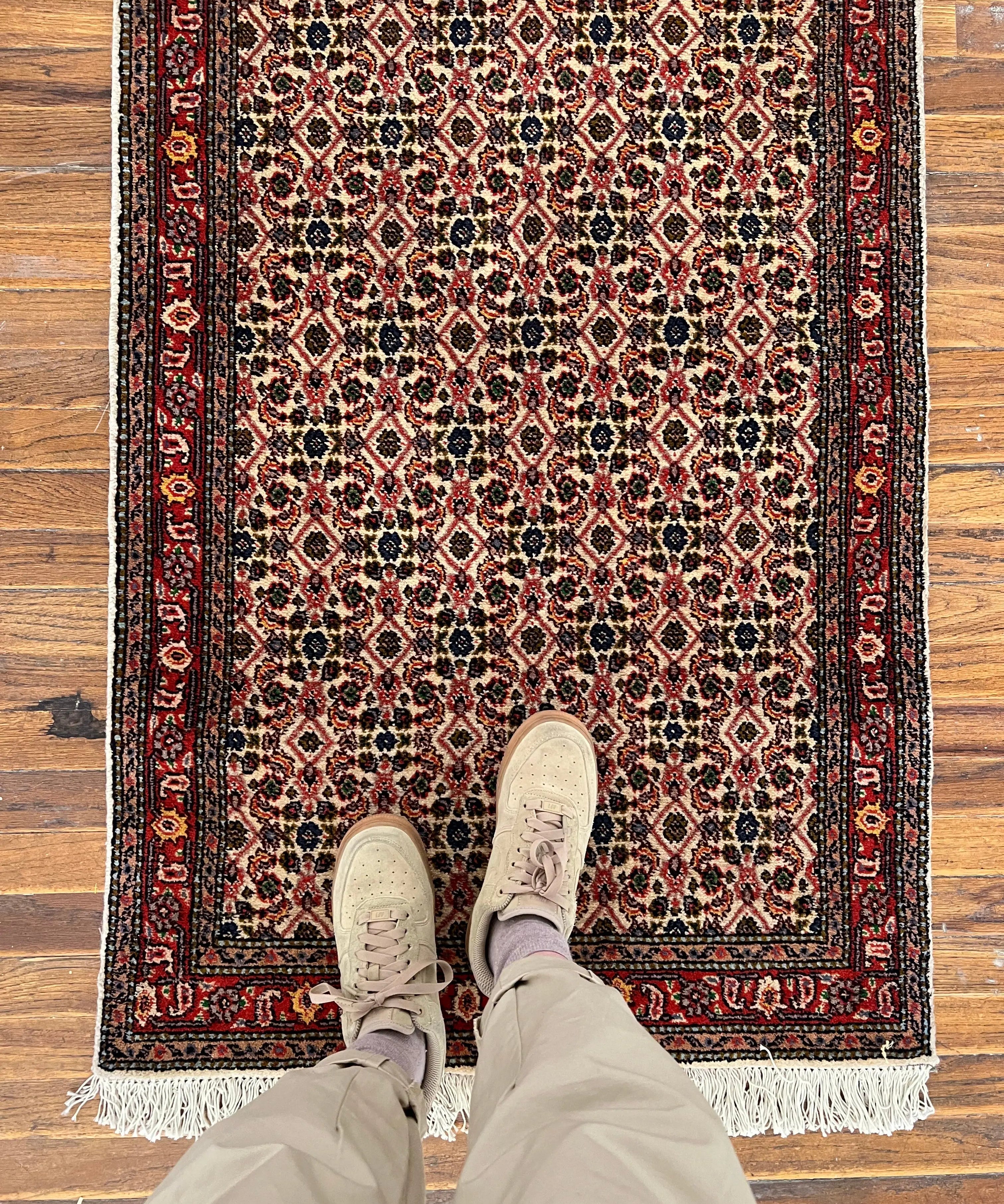 Persian-style runner rug with red, cream, and navy geometric medallion pattern and fringe