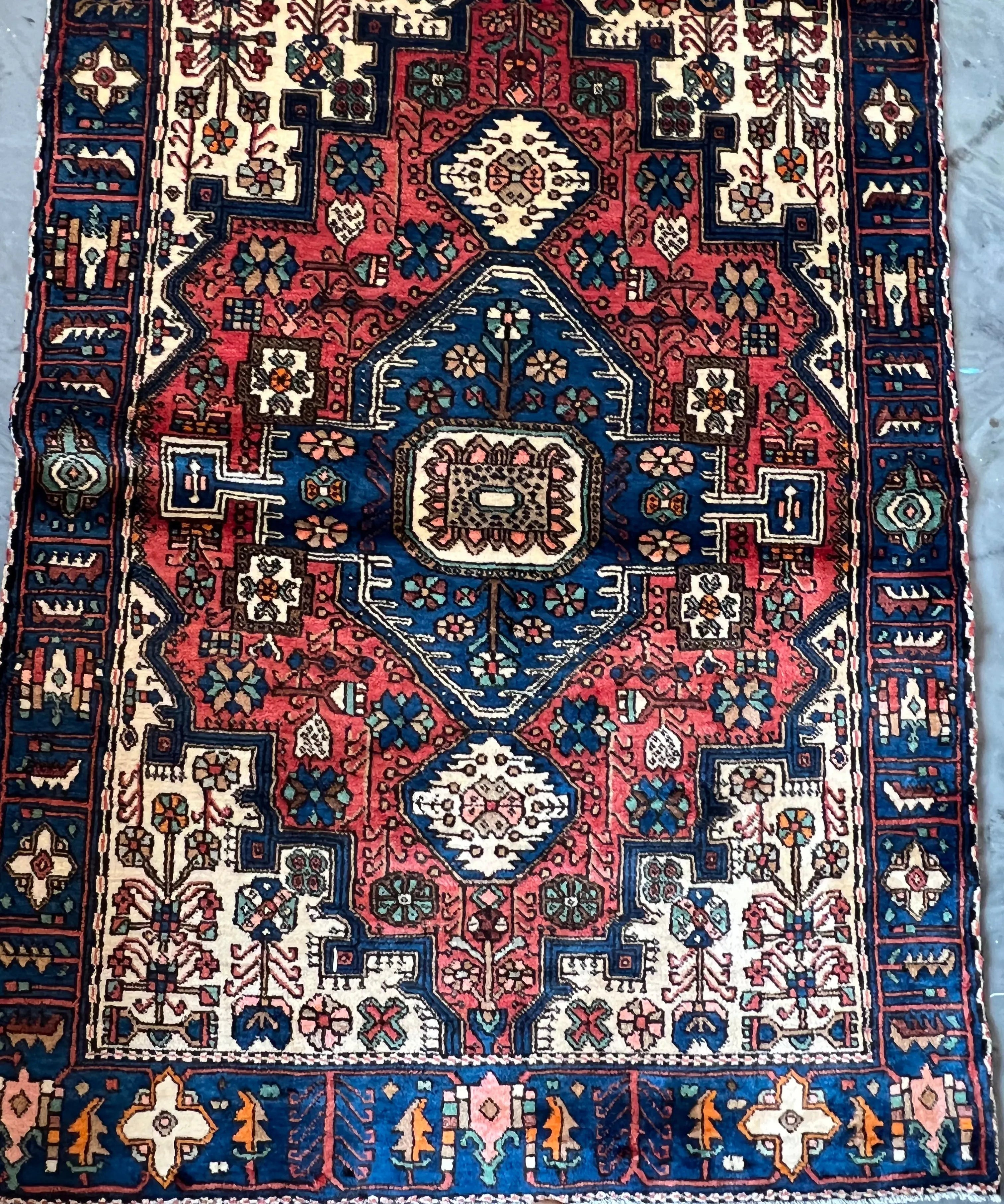 Nahavand rug close-up with blue, red and cream medallion and repeating corner motifs