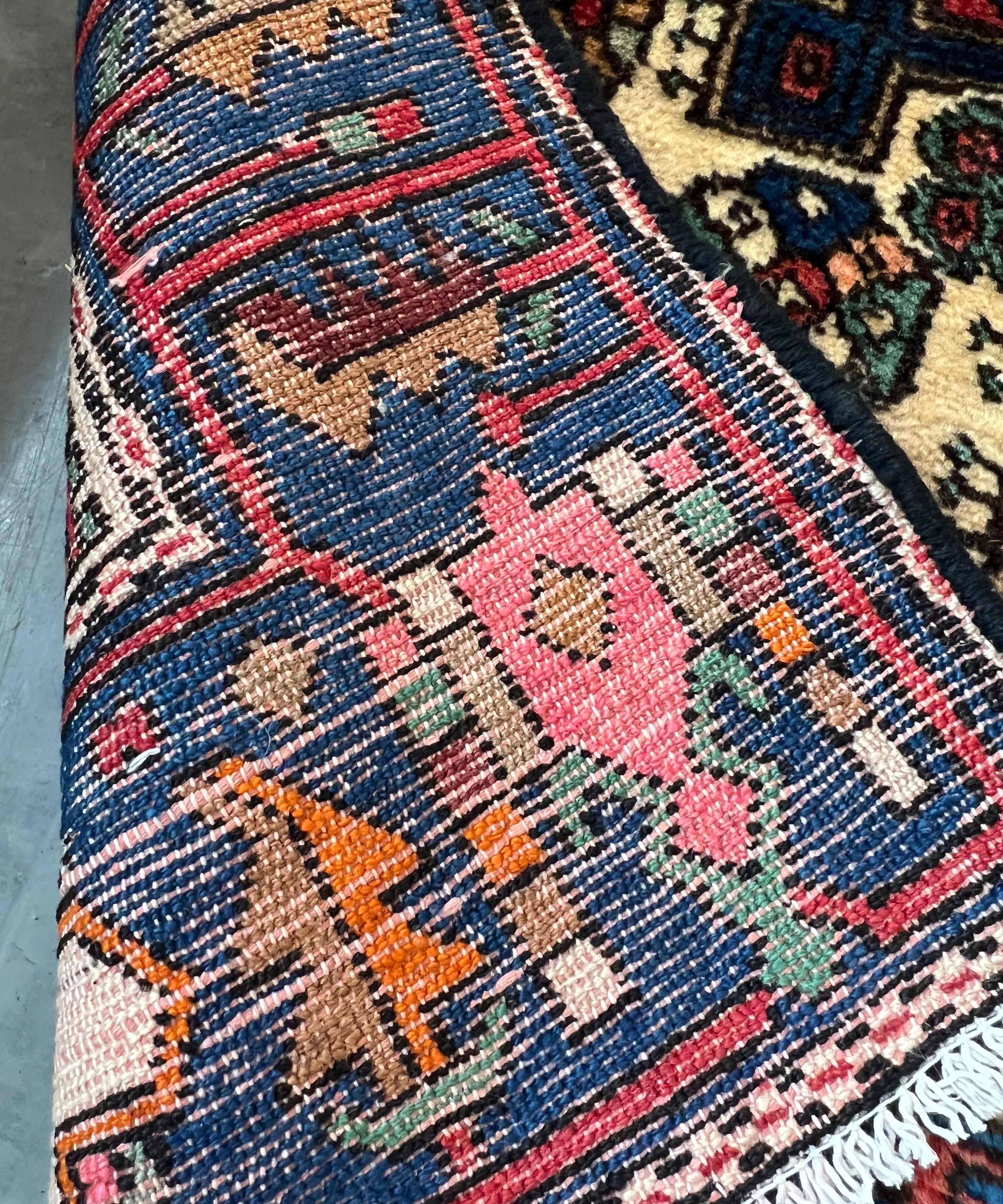 Nahavand rug corner detail with multicolor weave and short fringes in blue, pink and cream