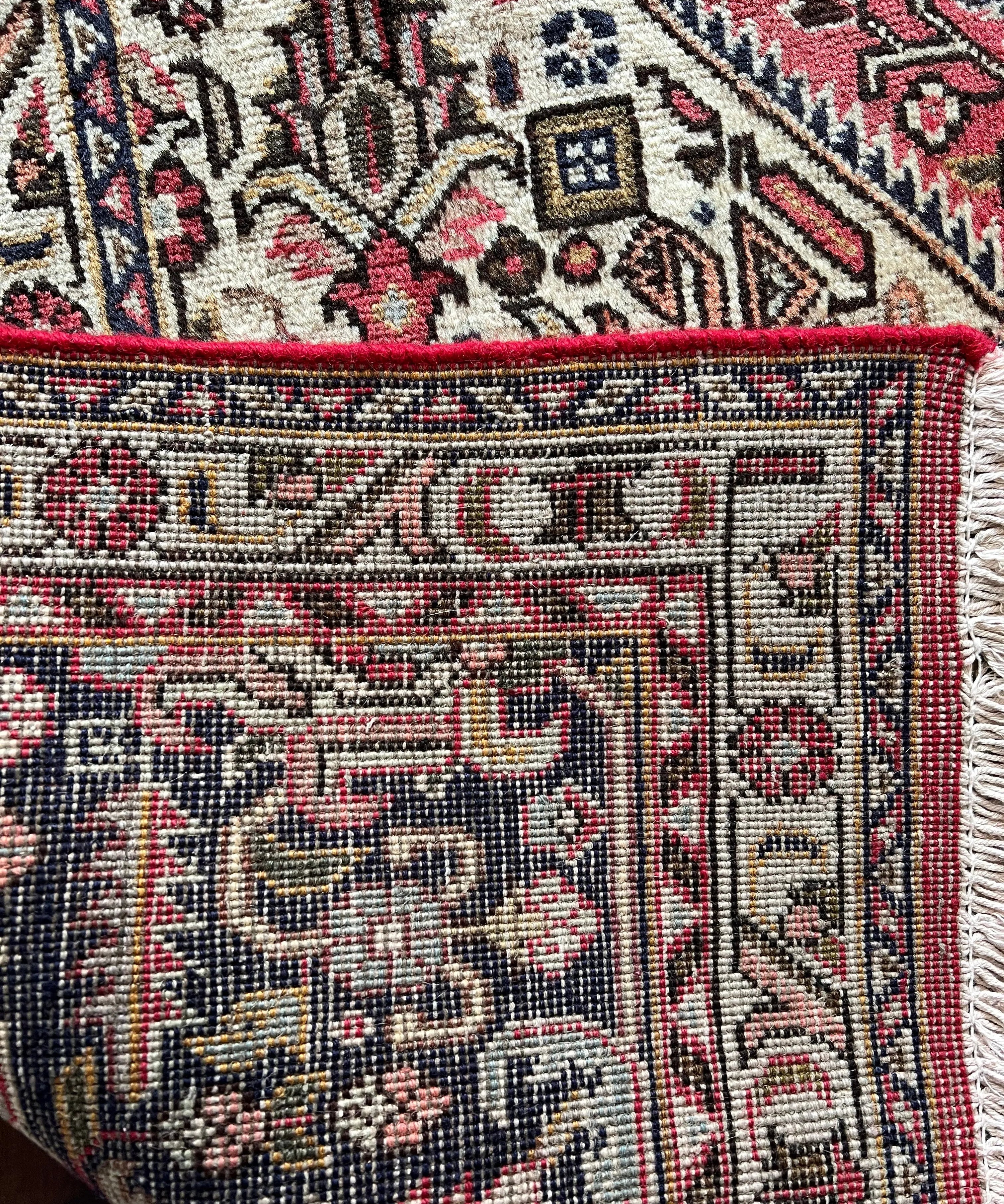 Persian rug close-up corner with red, cream, and dark blue floral and geometric patterns