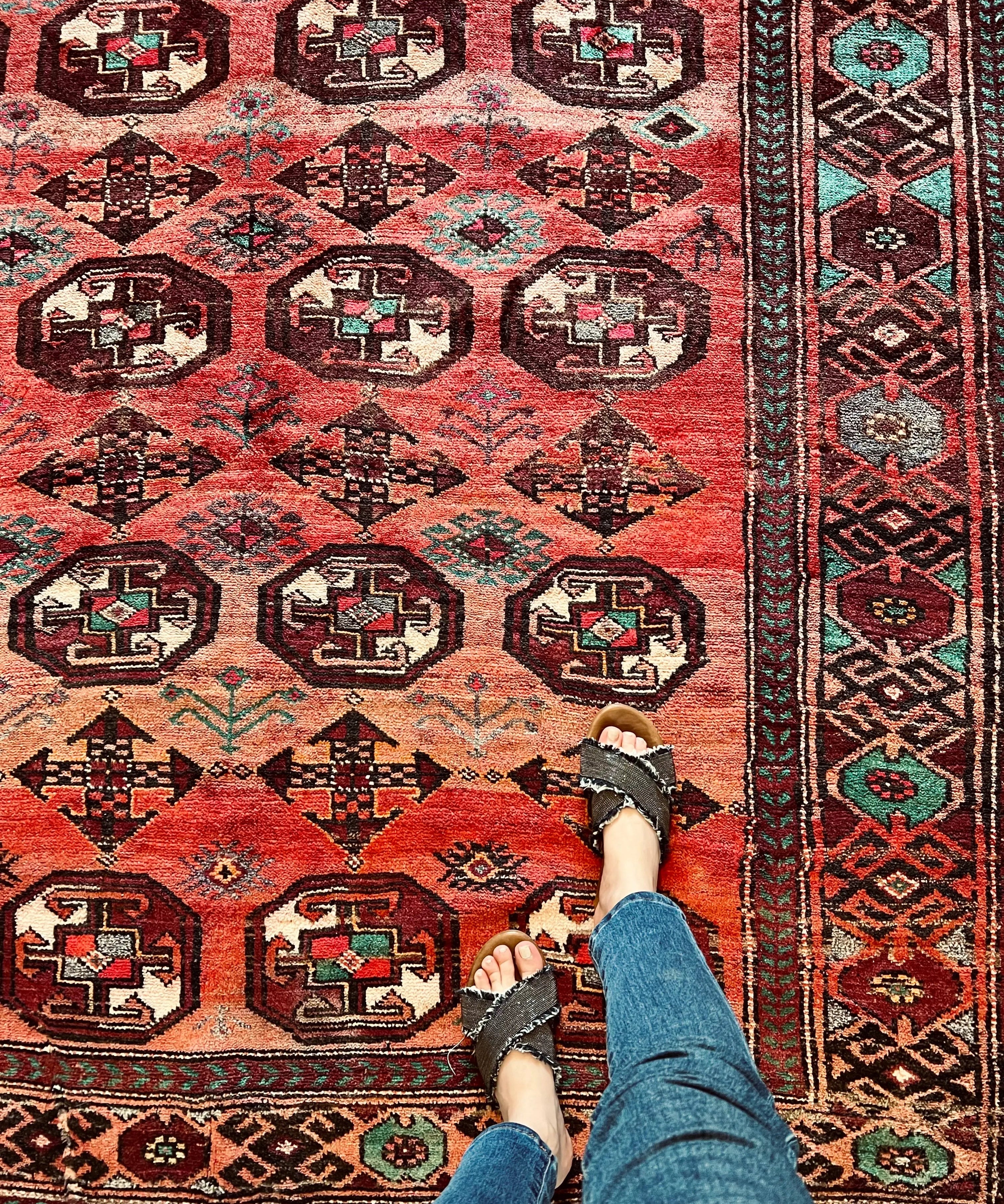 Persian tribal rug with red field and teal medallion pattern, geometric border